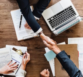 Working at a desk with documents and laptop, handshake