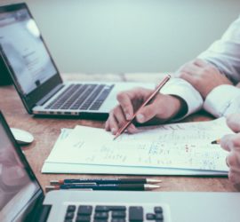 person working on a laptop with notes