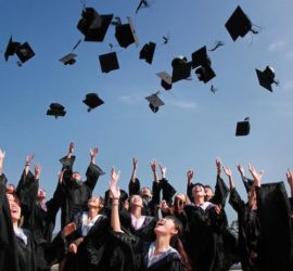 students in graduation gowns throwing caps