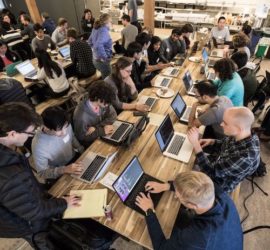 people working on laptops at long desk