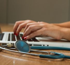 Woman working at laptop with stethoscope