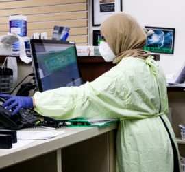 Scientist in full scrubs working on a computer