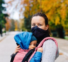 Woman with baby in face mask outside