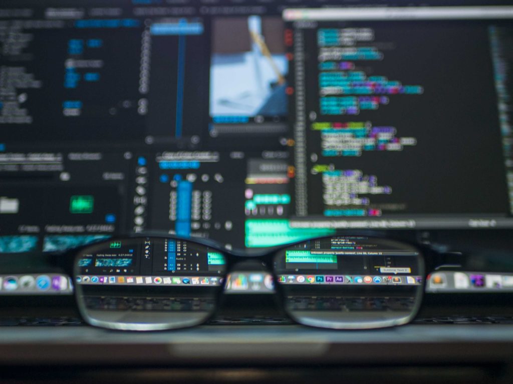 Image of computer screen with code as seen through glasses lying on a table