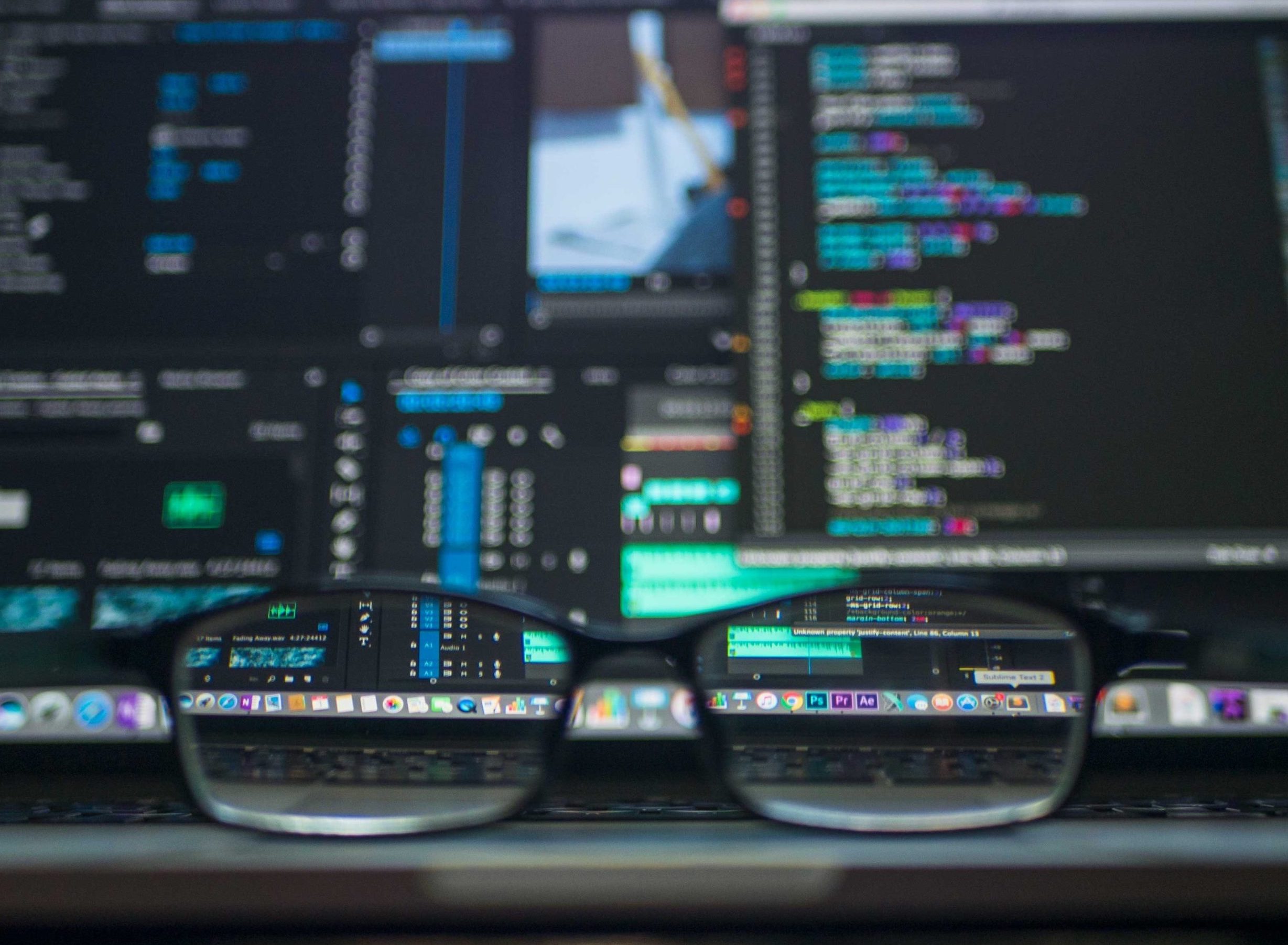 Image of computer screen with code as seen through glasses lying on a table