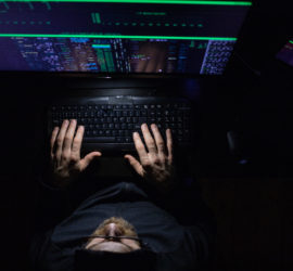 Stock photo of a man in a dimly lit room with computer screens