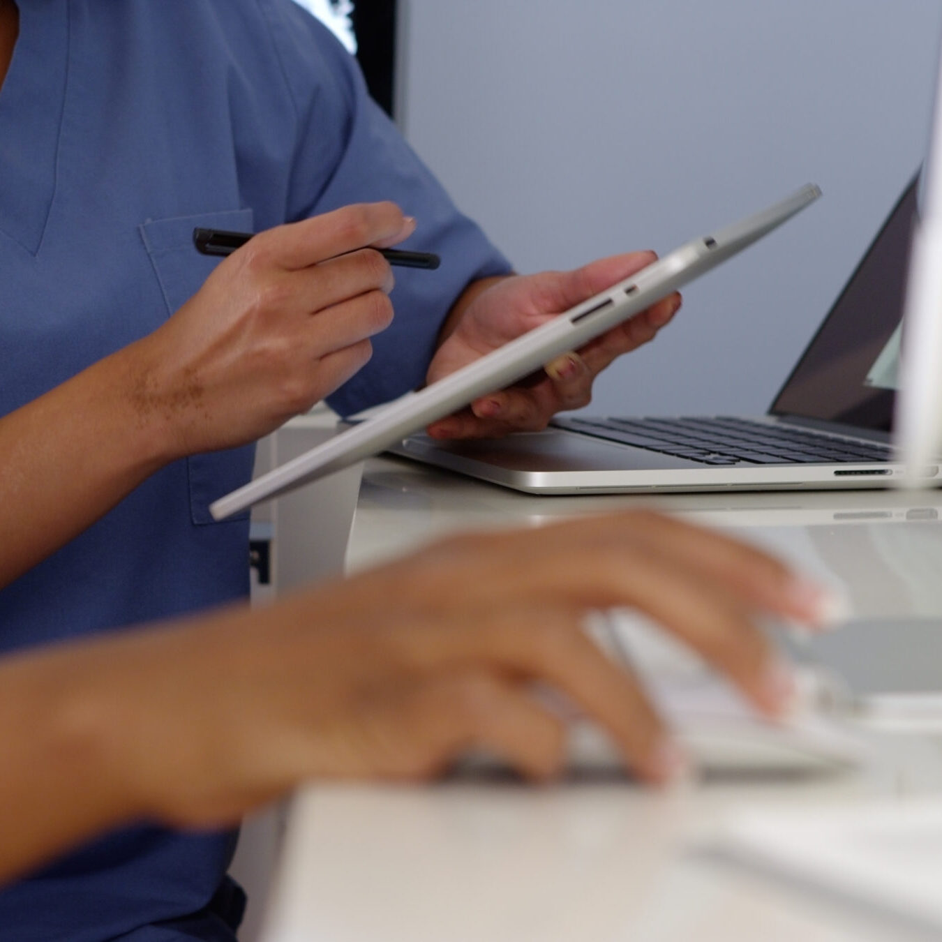 Close up hands of two female doctors working with computers