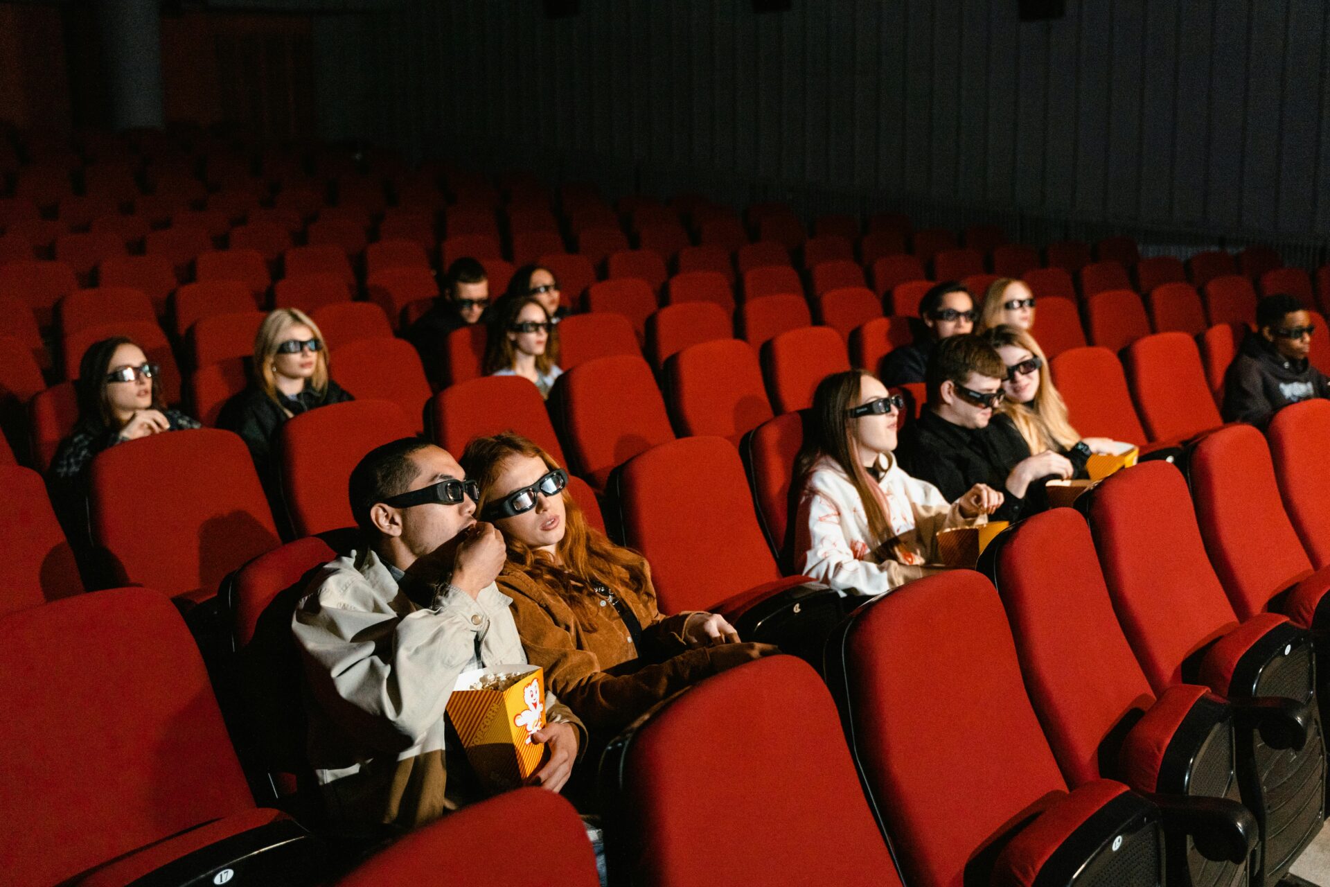 People in a movie theater wearing 3D glasses watching a film