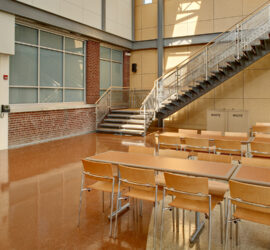 Large room at Bergen County Academies, with a staircase in the corner and rows of large tables